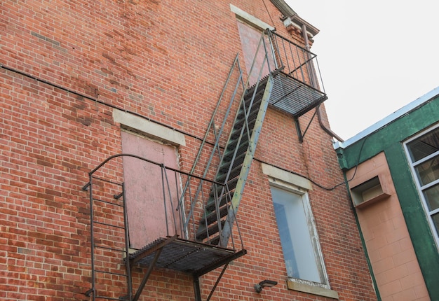 A fire escape on a brick building with a green metal staircase.