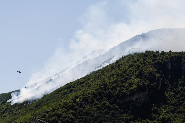 Fire fighting helicopter dropping water on forest fire at mountain in Sant'Antonio Abate Campania Italy