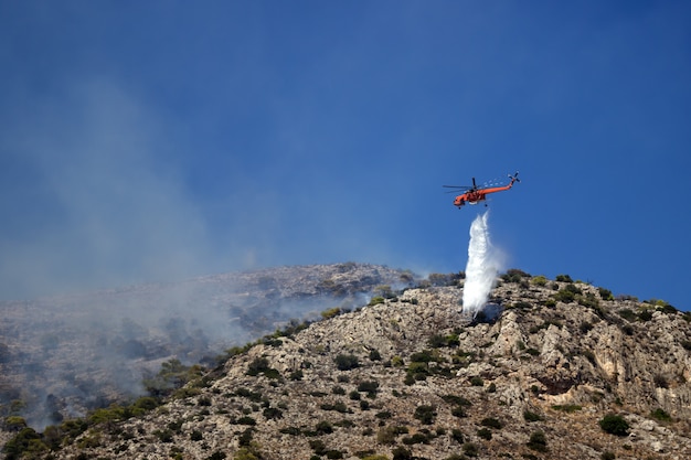 Fire helicopter extinguishes the fire on the hillside . Greece. The end of the summer.