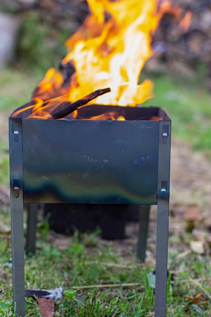 A fire is burning in a metal grill. A large, bright flame of fire at close range. Outdoor recreation. 3