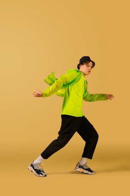 Fire. Old-school fashioned young man dancing isolated on yellow studio background. Artist fashion, motion and action concept, youth culture, fashion returning. Young caucasian curly boy.