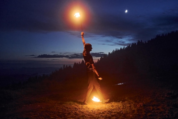 Fire show by man in night Carphatian mountains Beautiful landscape