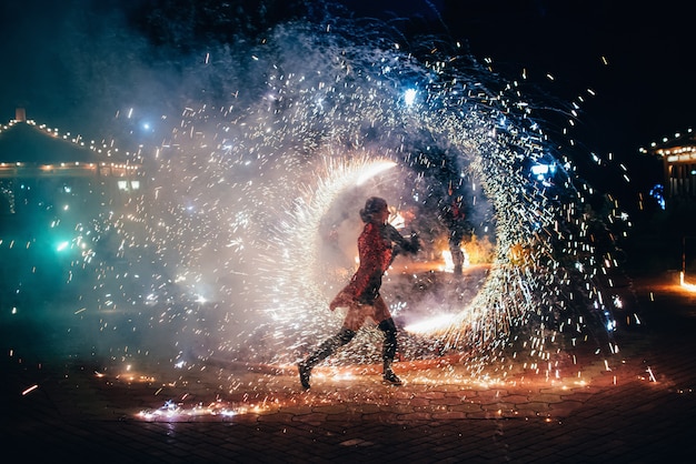 Fire show. Girl spins fiery sparkling torches