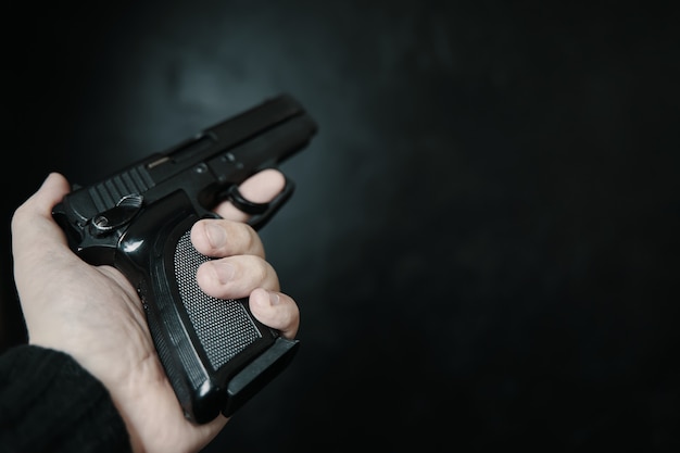 Firearm in mans hand first person view of gun criminal with pistol on black background defense or at...