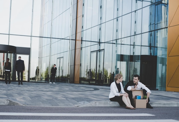 Fired businessman sitting on street