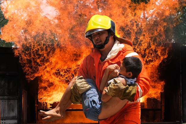 Firefighter holding child boy to save him in fire and smokeFiremen rescue the boys from fire