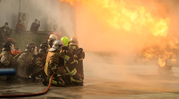 Firefighters using Twirl water fog type fire extinguisher to fighting with the fire flame from oil to control fire not to spreading out Firefighter and industrial safety concept