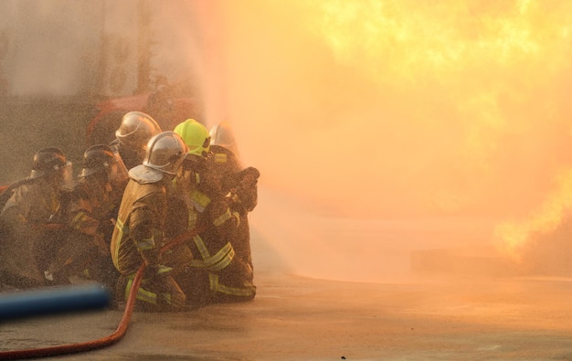 Firefighters using Twirl water fog type fire extinguisher to fighting with the fire flame from oil to control fire not to spreading out Firefighter and industrial safety concept