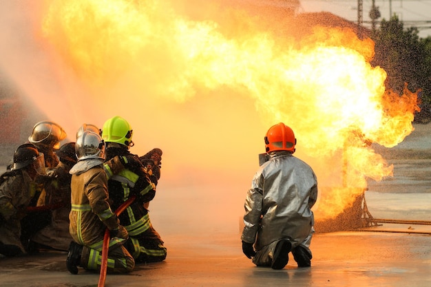 Firefighters using Twirl water fog type fire extinguisher to fighting with the fire flame from oil to control fire not to spreading out Firefighter and industrial safety concept