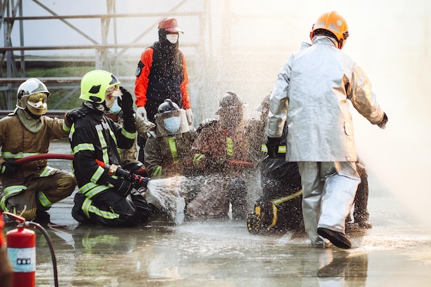 Firefighters using Twirl water fog type fire extinguisher to fighting with the fire flame from oil to control fire not to spreading out Firefighter and industrial safety concept