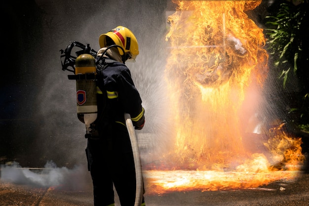 Firefighters with extinguisher spraying high pressure water to fighting the fire flame.