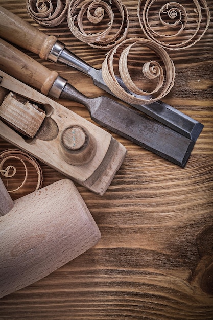 Firmer chisels shaving plane curled shavings wooden mallet on wood board construction concept.