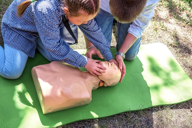 Photo first aid instruction on a mannequin a doctor teaches a teenager how to perform cpr