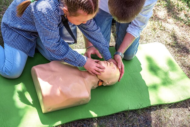 Photo first aid instruction on a mannequin a doctor teaches a teenager how to perform cpr