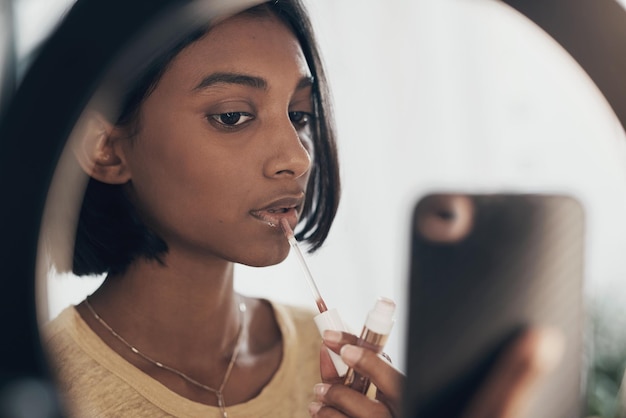 First comes the gloss up then comes the glow up Shot of a young woman applying makeup while filming a beauty tutorial at home