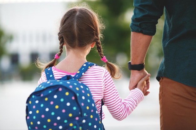 First day at school father leads a little child school girl in first grade