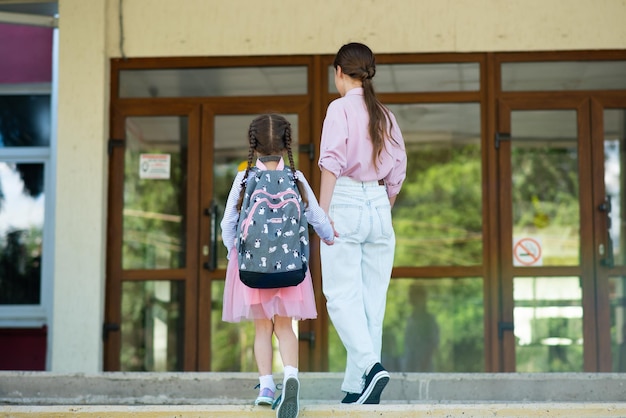 First day at school Older sister leads a little school girl in first grade Back to school