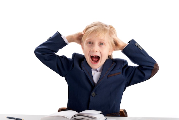 First grader boy fools around while performing lessons Difficulty concentrating in children Screaming fidget boy in school uniform