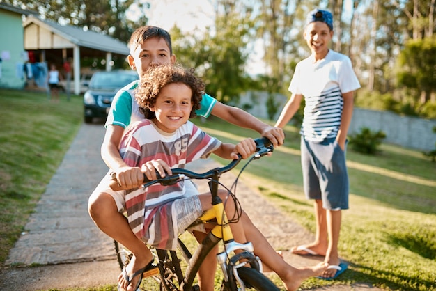 First rule of brotherhood Ride a bike together Shot of happy young brothers riding a bicycle together in their backyard