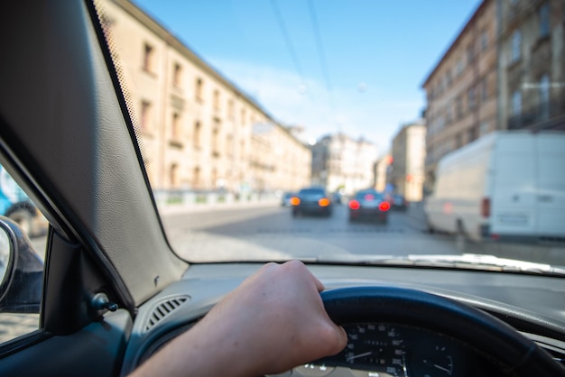 Firstperson view man driving car by city streets urban traffic