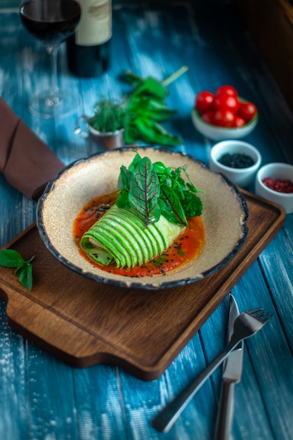 Fish baked with zucchini roll with vegetables and green salad in tomato sauce