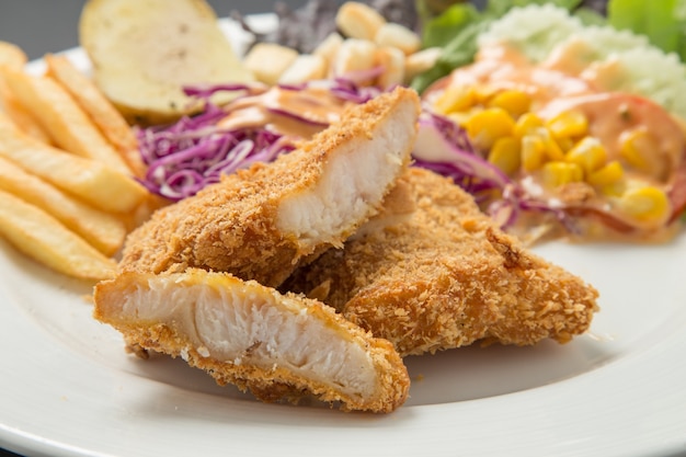 Fish dish - fried fish fillet with vegetables on black background