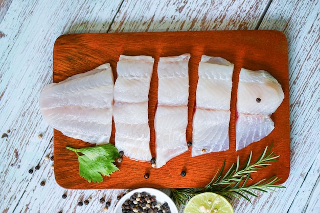 Fish fillet on wooden board with ingredients celery for cooking fresh raw pangasius fish fillet with meat dolly fish tilapia striped catfish