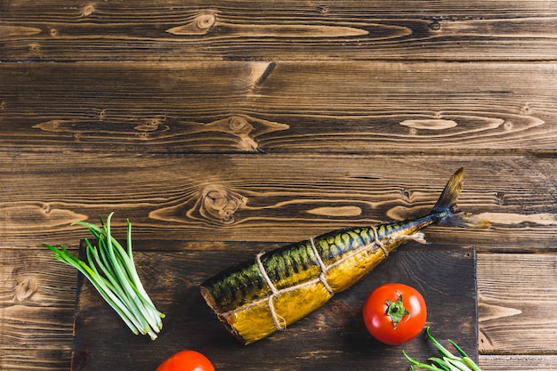 Fish mackerel smoked on a Board with tomatoes and pepper 