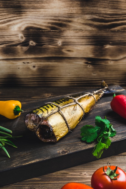 Fish mackerel smoked on a Board with tomatoes and pepper 