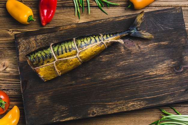 Fish mackerel smoked on a Board with tomatoes and pepper