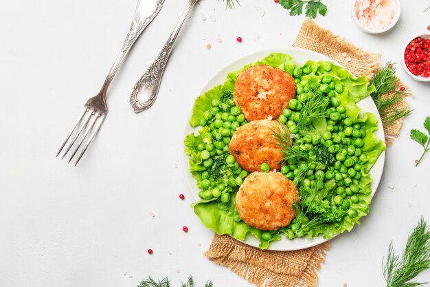 Fish meatballs or cutlets from sea cod with green vegetables top view