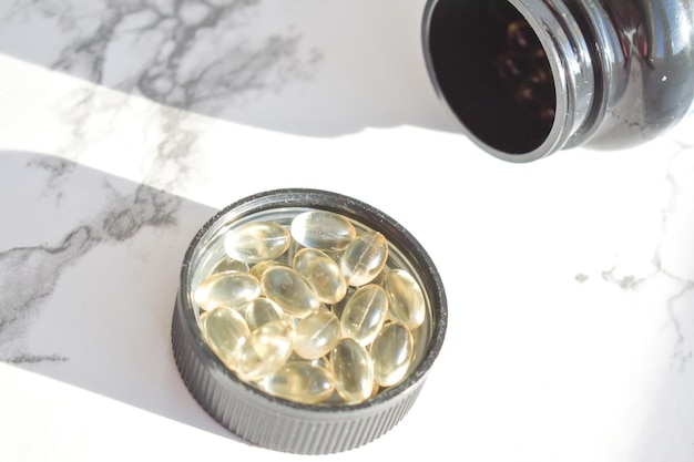 Fish oil capsules with omega3 and vitamin D in a jar on a white concrete surface