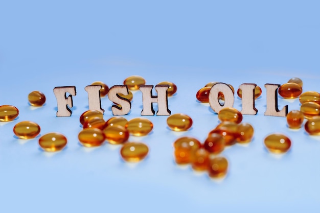 Fish oil pills in a golden jelly shell with the letters Fish oil on a paper background