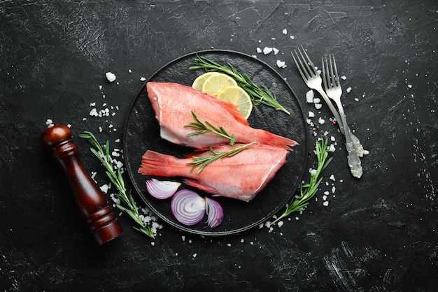 Fish raw snapper with lemon and rosemary On a black background Top view Free space for your text