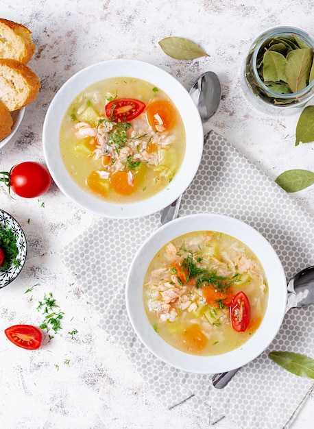 Fish soup with salmon vegetables and rice in white bowl Top view above