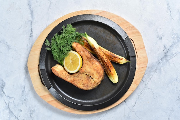 Fish steak with baked zucchini and herbs on a wooden board. Fish dishes. Top view