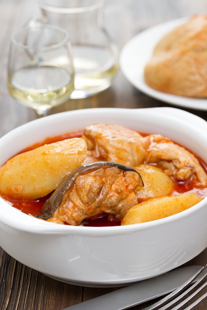 Fish stew on white bowl on wooden surface