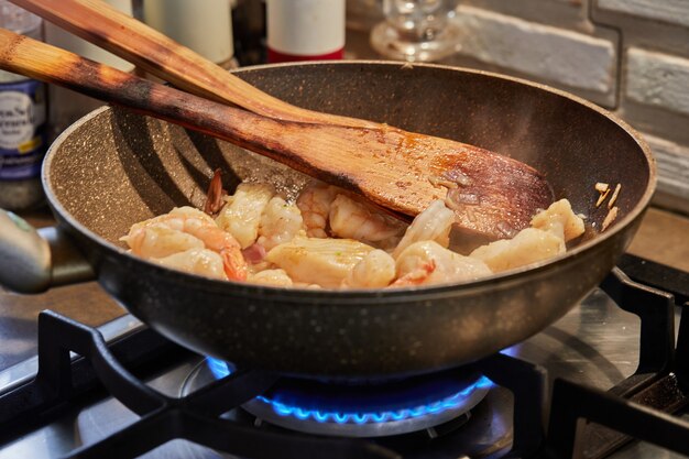 Fish with mushrooms and shrimps are fried in oil in pan, a step-by-step recipe from the Internet.