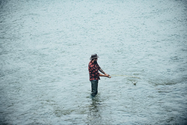 Fisher man in water catching fish top view fisherman with rod spinning reel on river bank man catchi