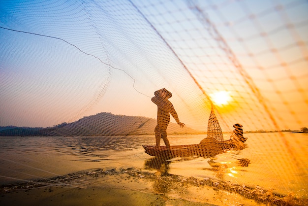 Fisherman on boat river sunset Asia net using on wooden boat casting net sunset or sunrise