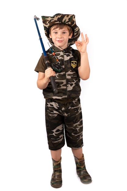 A fisherman boy in a fishing suit and hat with a fishing rod shows ok Fishing