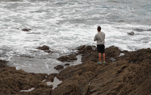 Fisherman casting the rod from the rocks