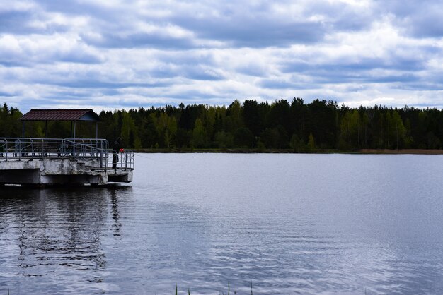 Fisherman catches fish from a pier on a forest lake