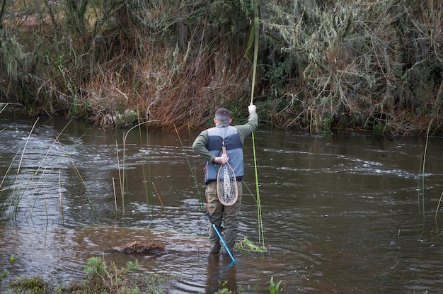 Fisherman fly fishing rainbow trout on mountain in beautiful scenary