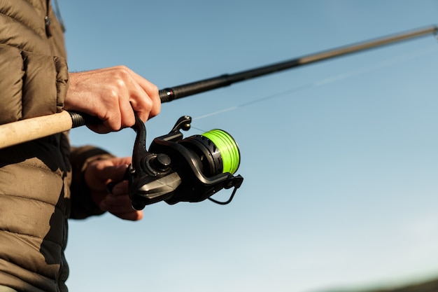 Fisherman hands holding fishing rod close up