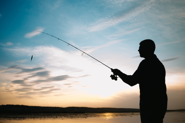 Fisherman holding the spinning rod by the lake