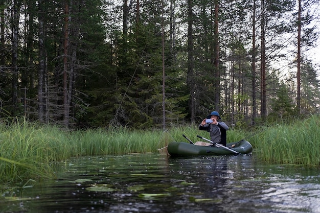 Fisherman on an inflatable boat photographs a beautiful morning landscape on a smartphone camera