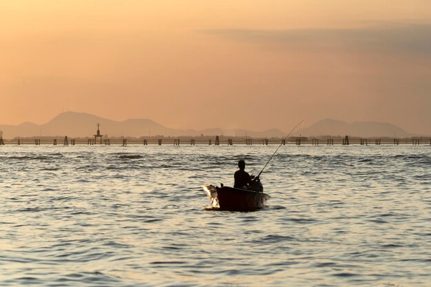 Fisherman silhouette at Sunset in Venice lagoon chioggia harbor from a boat