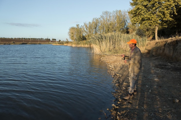 Fisherman standing on the riverside and trying to catch a fish Sport recreation lifestyle