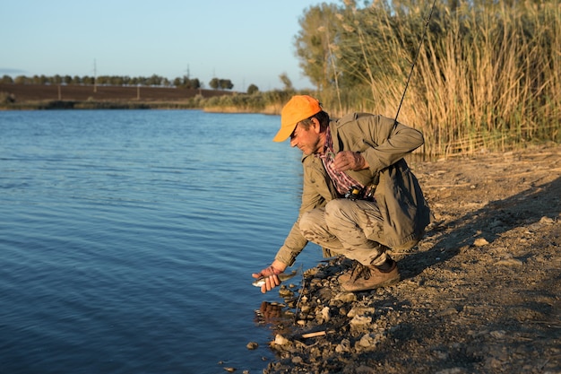 Fisherman standing on the riverside and trying to catch a fish. Sport, recreation, lifestyle.